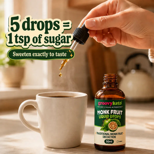 A hand holds a glass dropper above a white mug, with a bottle of Groovy Keto Monk Fruit Liquid Drops beside it on a kitchen counter. Large text reads '5 drops = 1 tsp of sugar' and 'Sweeten exactly to taste'.