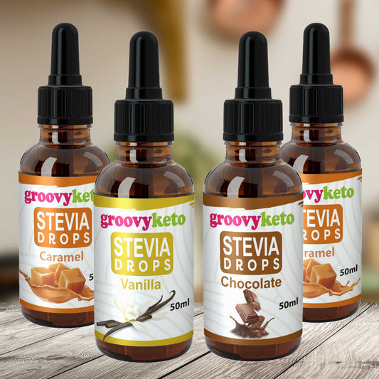 Four bottles of Groovy Keto liquid stevia drops in different flavors including Vanilla, Chocolate, Caramel, and Pure, displayed on a wooden surface.