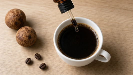 Amber glass dropper adding a drop of monk fruit decoction to a mug of black coffee beside dried monk fruits