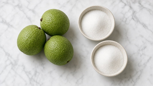Fresh monk fruits beside two bowls of granulated sweetener